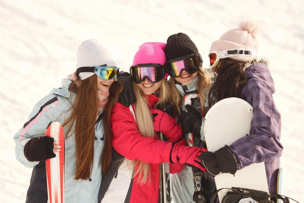 A group of women with snowboards in the snow on a girls weekend away