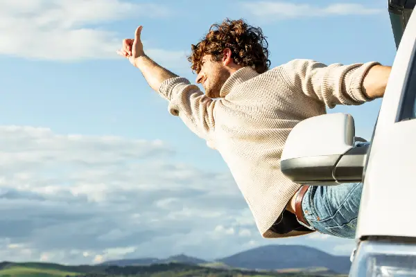 Leaving cert or leavers trip group member leaning out of a campervan on a road trip