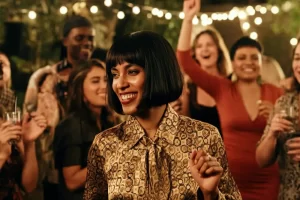 A woman dressed in a smart outfit and smiling with a crowd of people behind her in a garden party with fairy lights for a 40th birthday party milestone