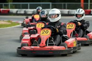 A group of adults in a go karting race on an outdoor track