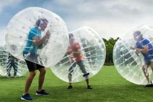 A group of adults playing a game of bubble football in inflatable round balls