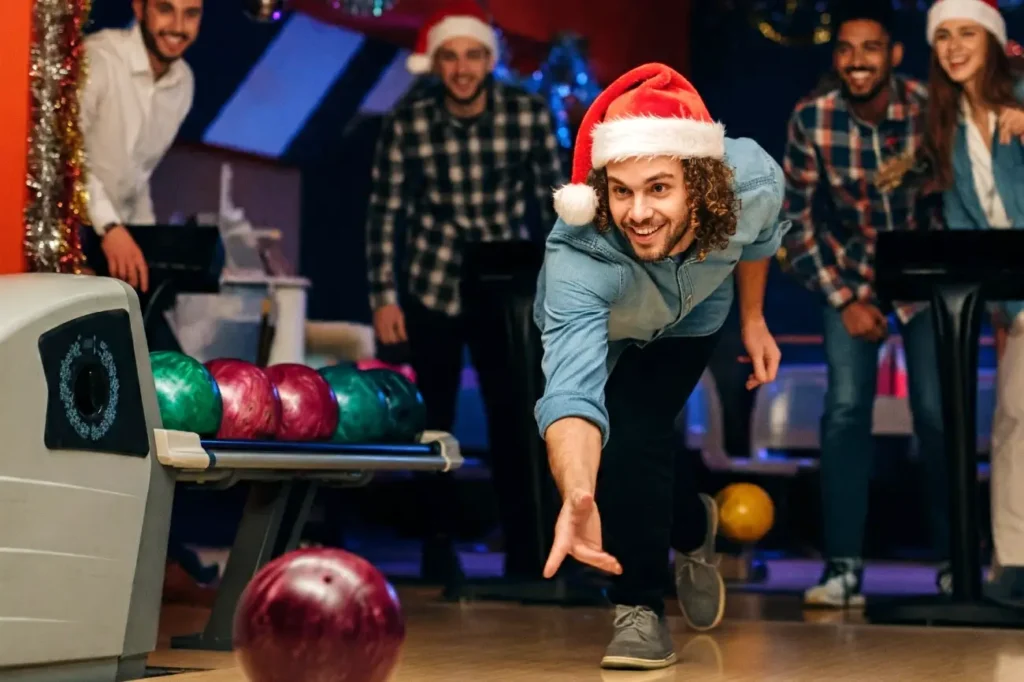 A man throwing a bowling ball down the lane on their last minute work Christmas party ideas party